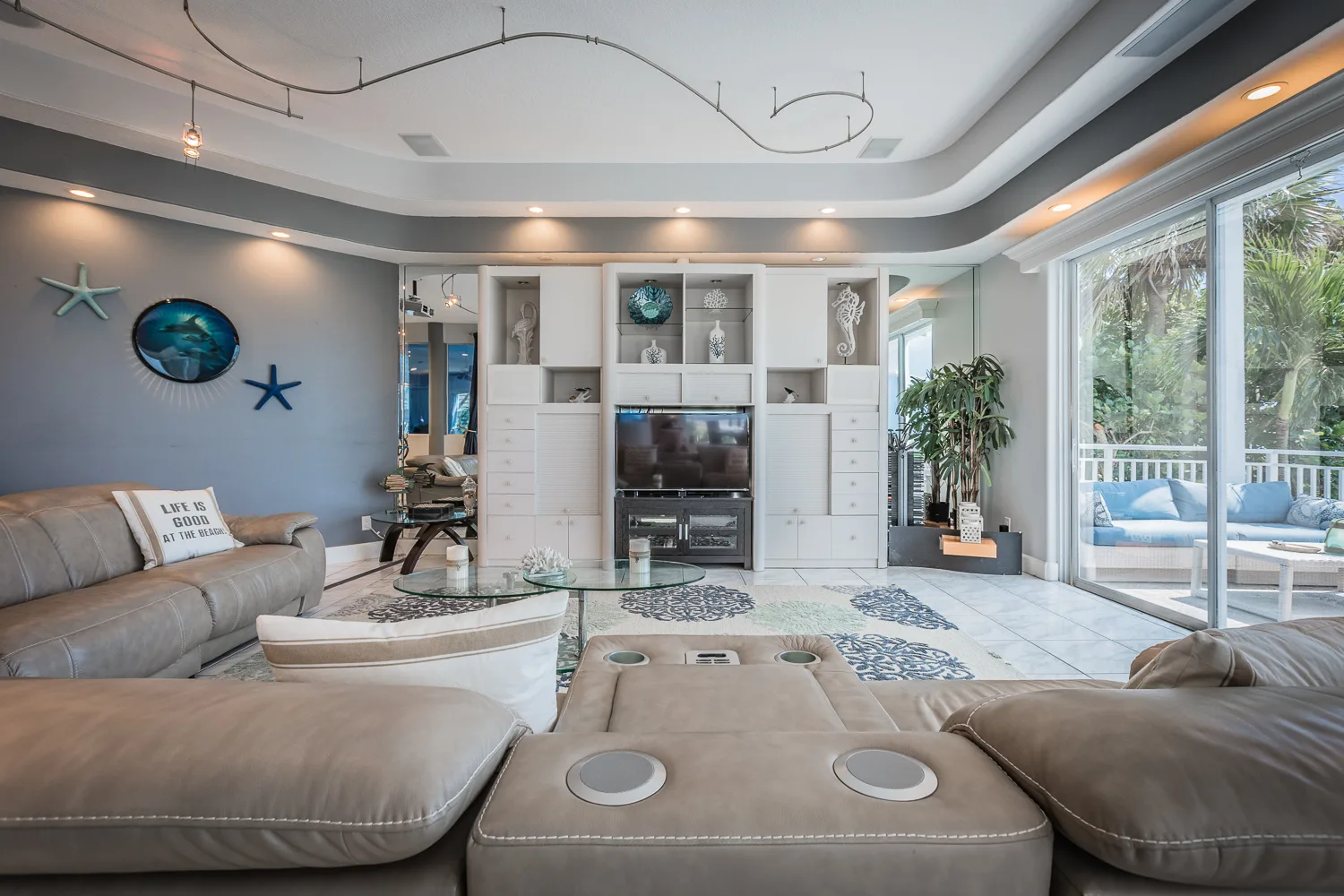 Coastal living room with leather sectionals, built-in shelving, and balcony access