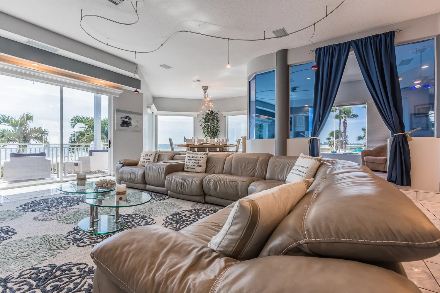 Spacious living room with wraparound leather sectional and floor-to-ceiling water views