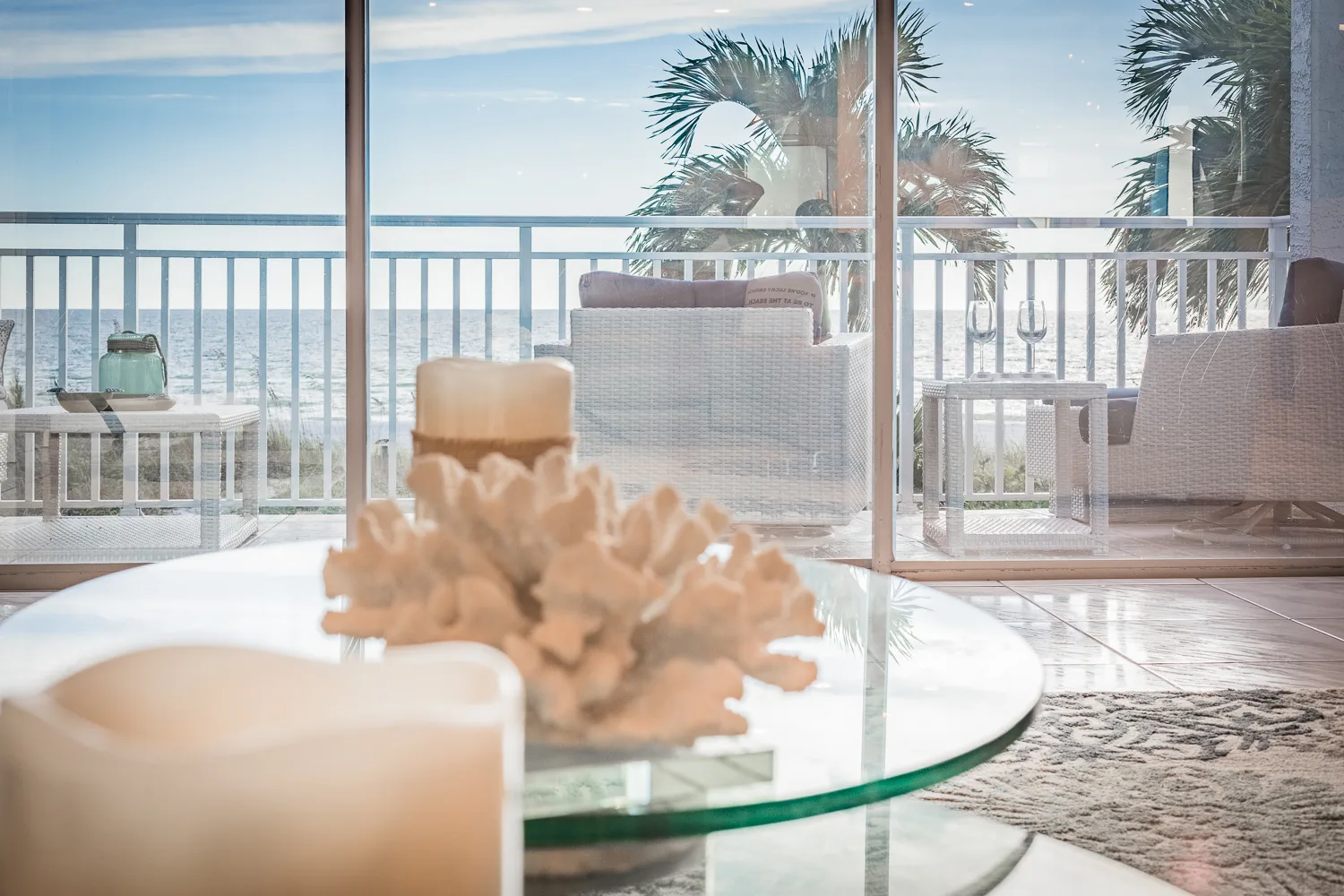 Coral and candle centerpiece on glass table before an ocean-view balcony