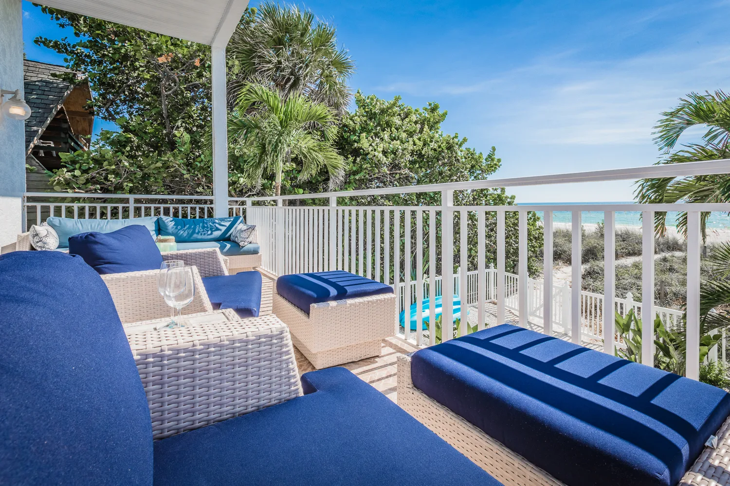 Navy cushioned loungers on a balcony amid palms overlooking the shoreline