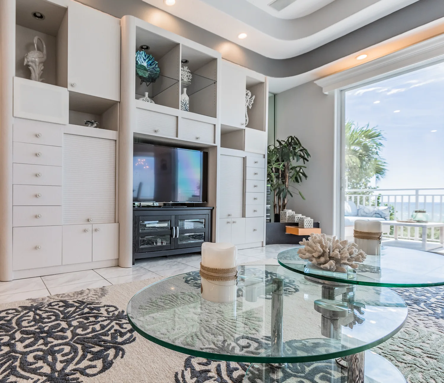White built-in media wall with round glass tables and balcony view