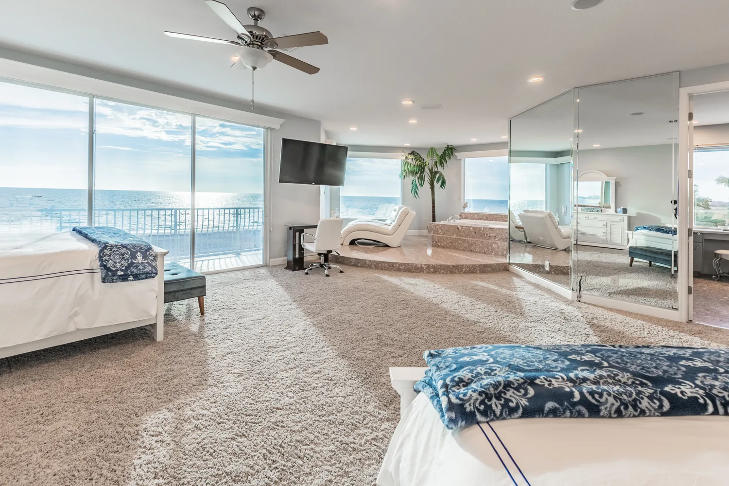 Expansive oceanfront primary suite with two beds, mirrored walls and balcony