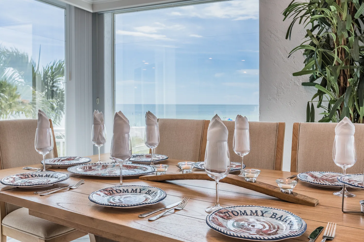 Dining table set with patterned plates facing a wide ocean-view window