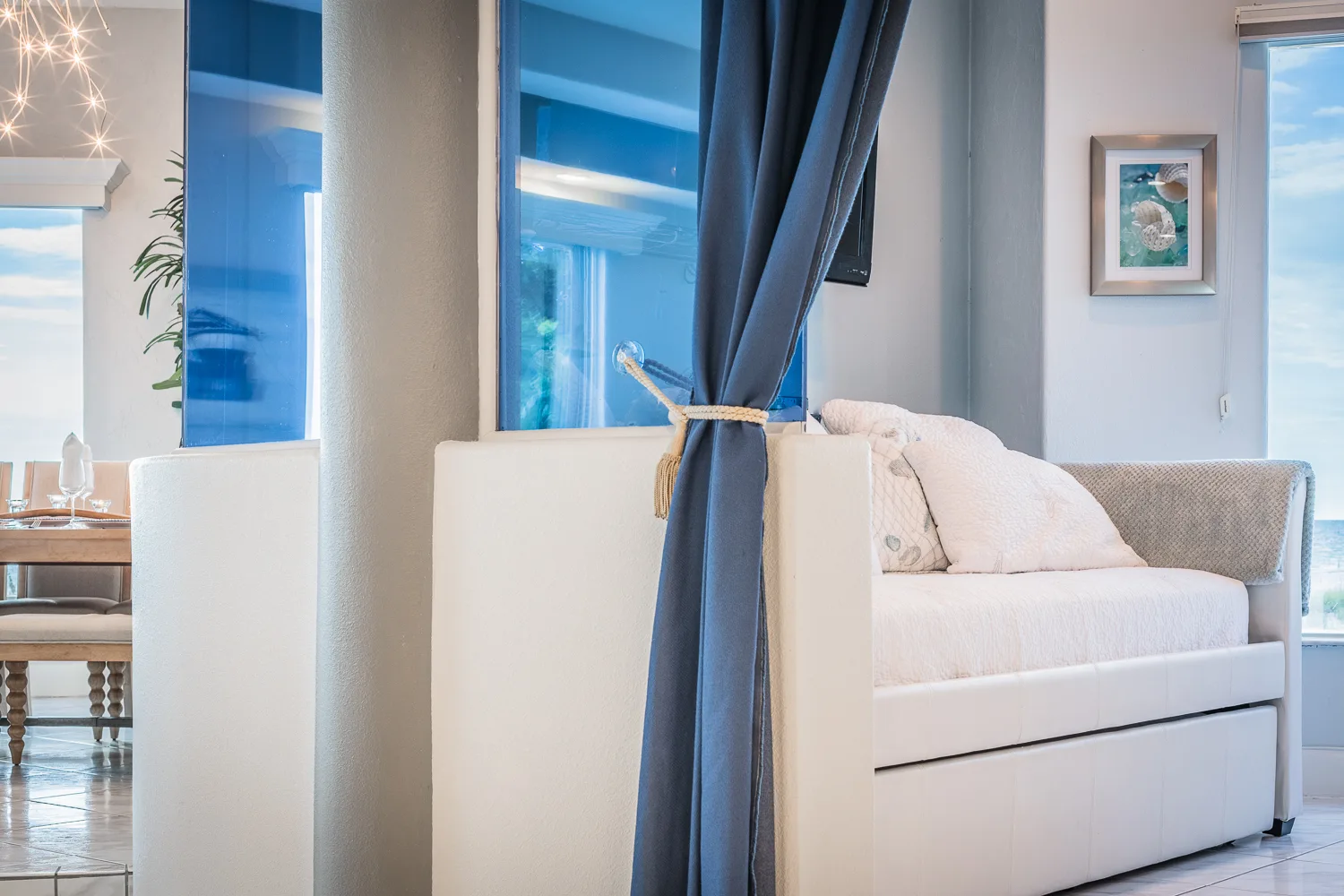 White daybed with trundle beside a column and blue drapery