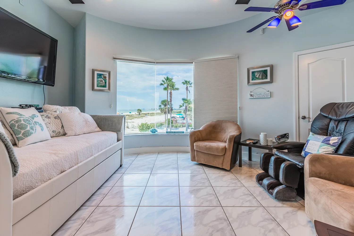 Coastal den with daybed, massage chair and curved window overlooking the beach