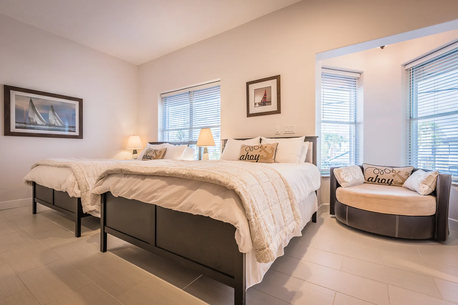 Bedroom with two beds, ahoy pillows, nautical art and a round cuddle chair
