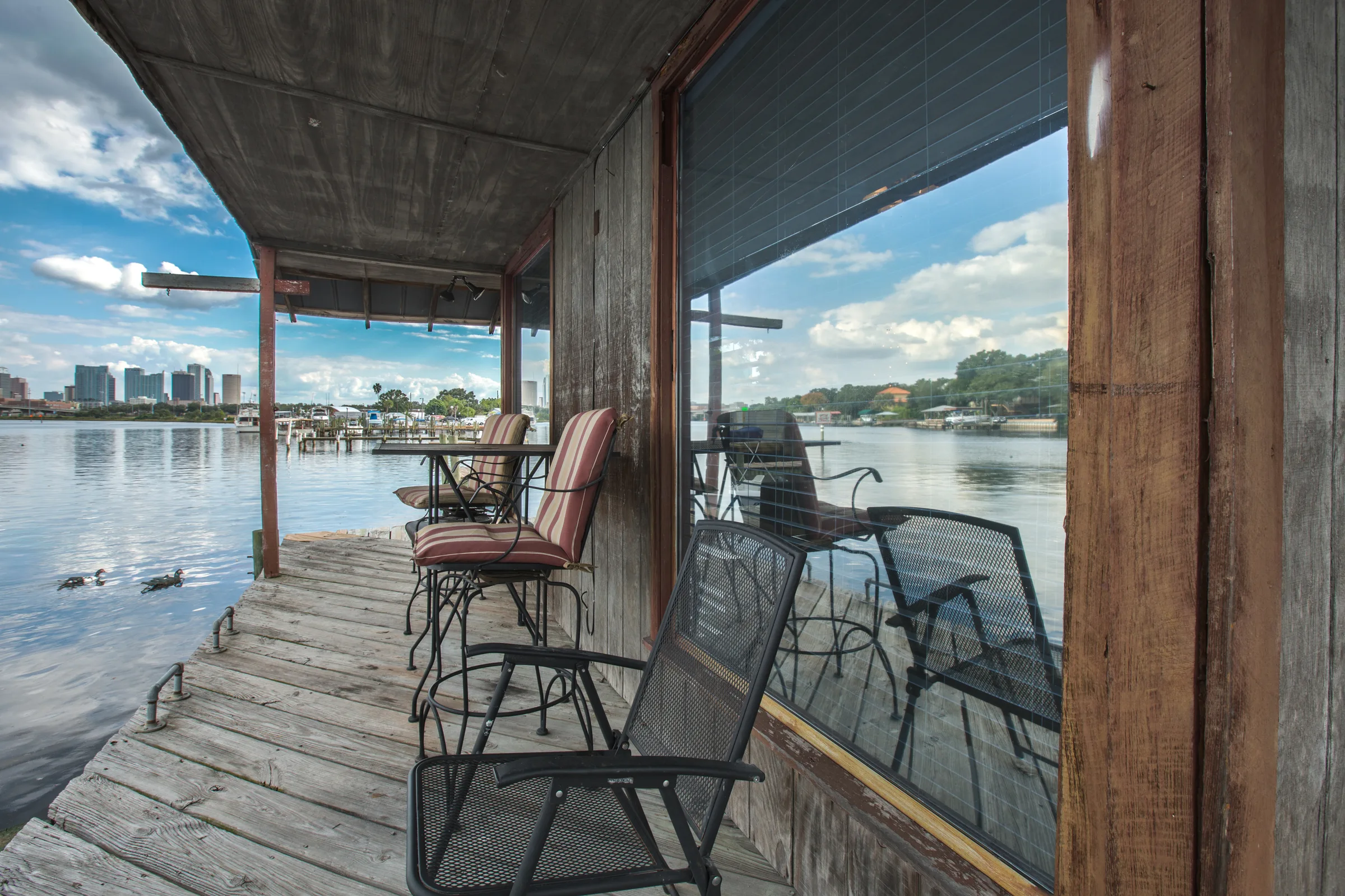 Patio chairs on weathered dockside porch overlooking wide water and skyline