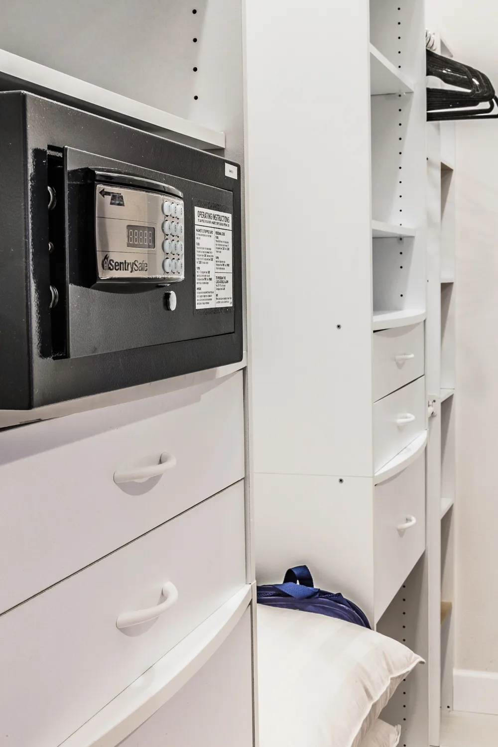 Digital safe mounted among white closet shelving and drawers