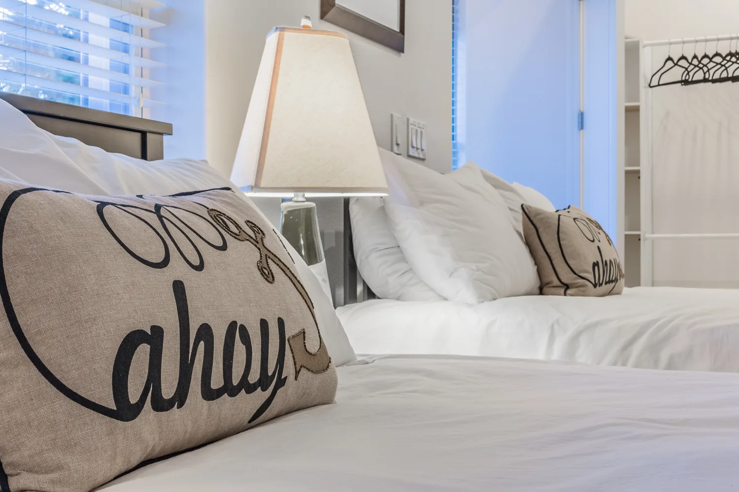 Twin beds dressed in white linens with ahoy accent pillows
