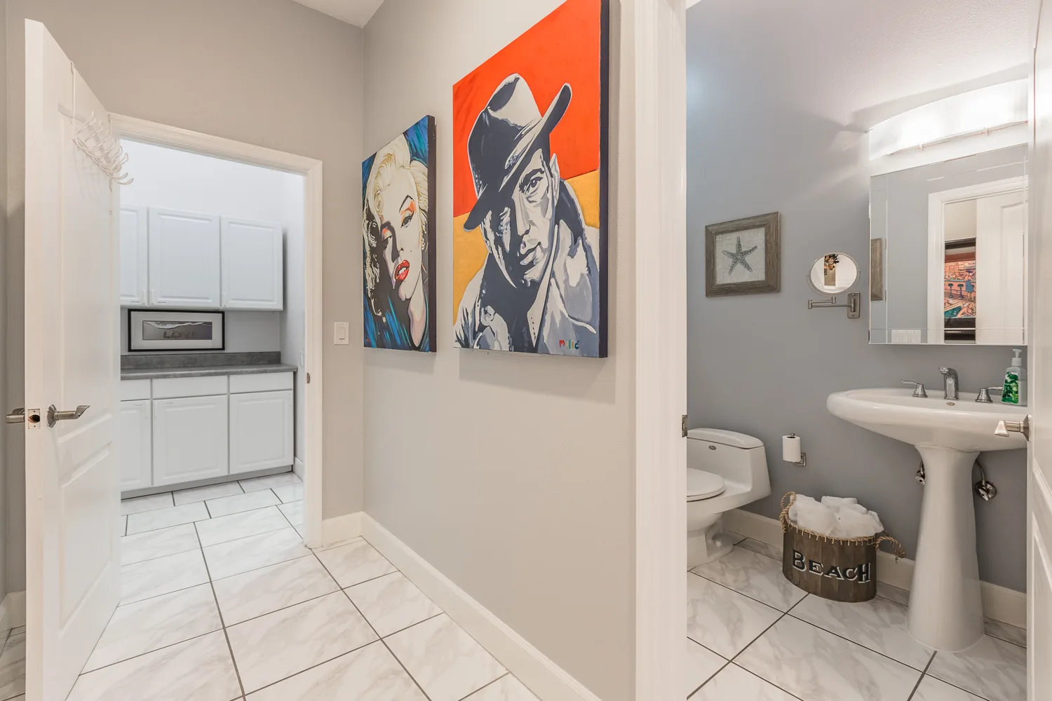 Hallway with pop-art portraits leading to a kitchenette and powder room