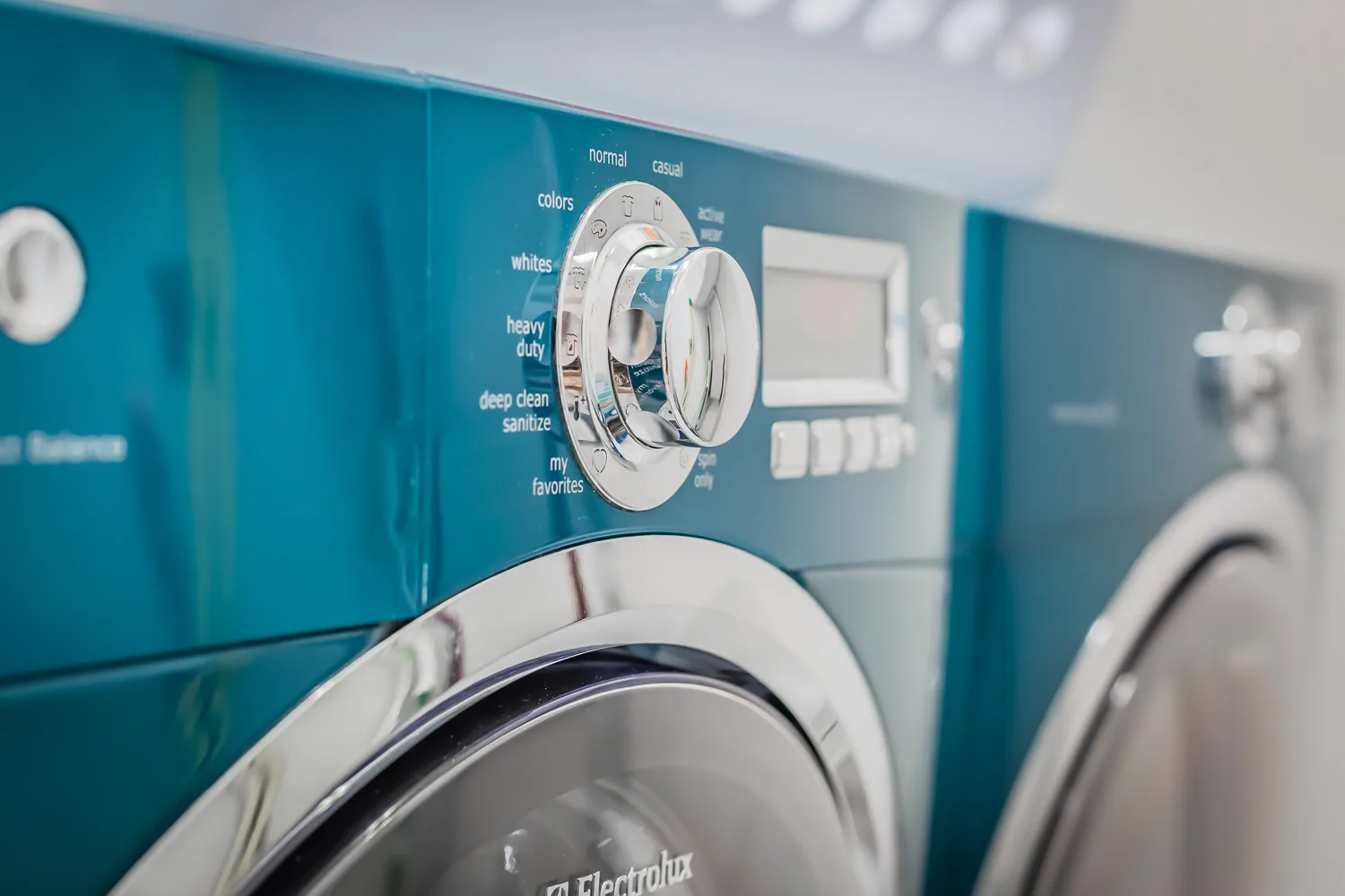 Close-up of teal front-load washer and dryer control dials