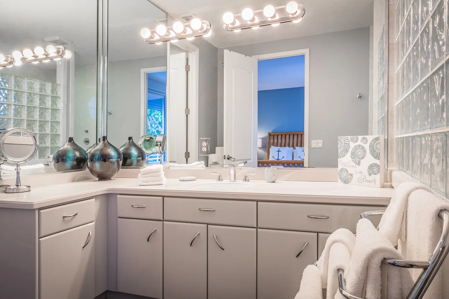 Vanity with lighted mirrors, glass block accents and rolled towels