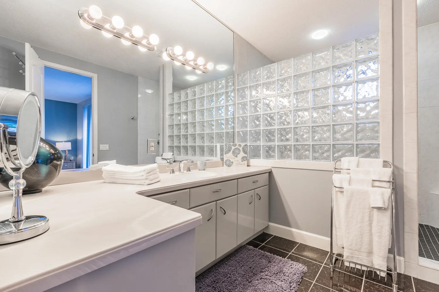 Bright bathroom with long vanity, glass block wall and towel rack