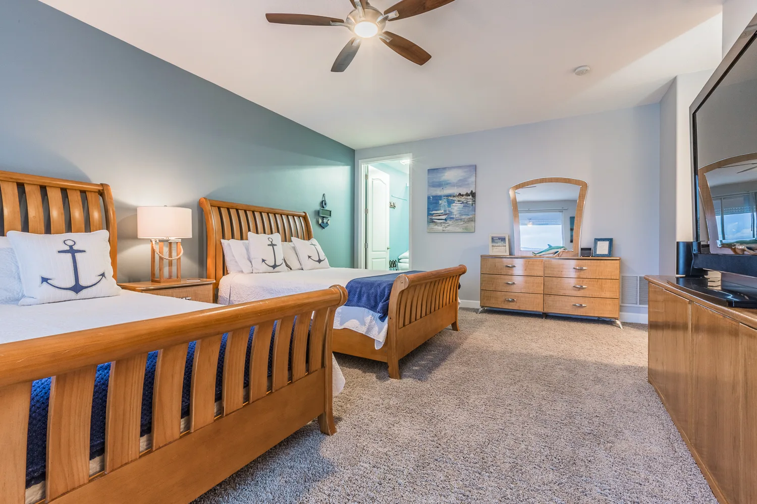 Nautical bedroom with two wood sleigh beds, dresser and ceiling fan