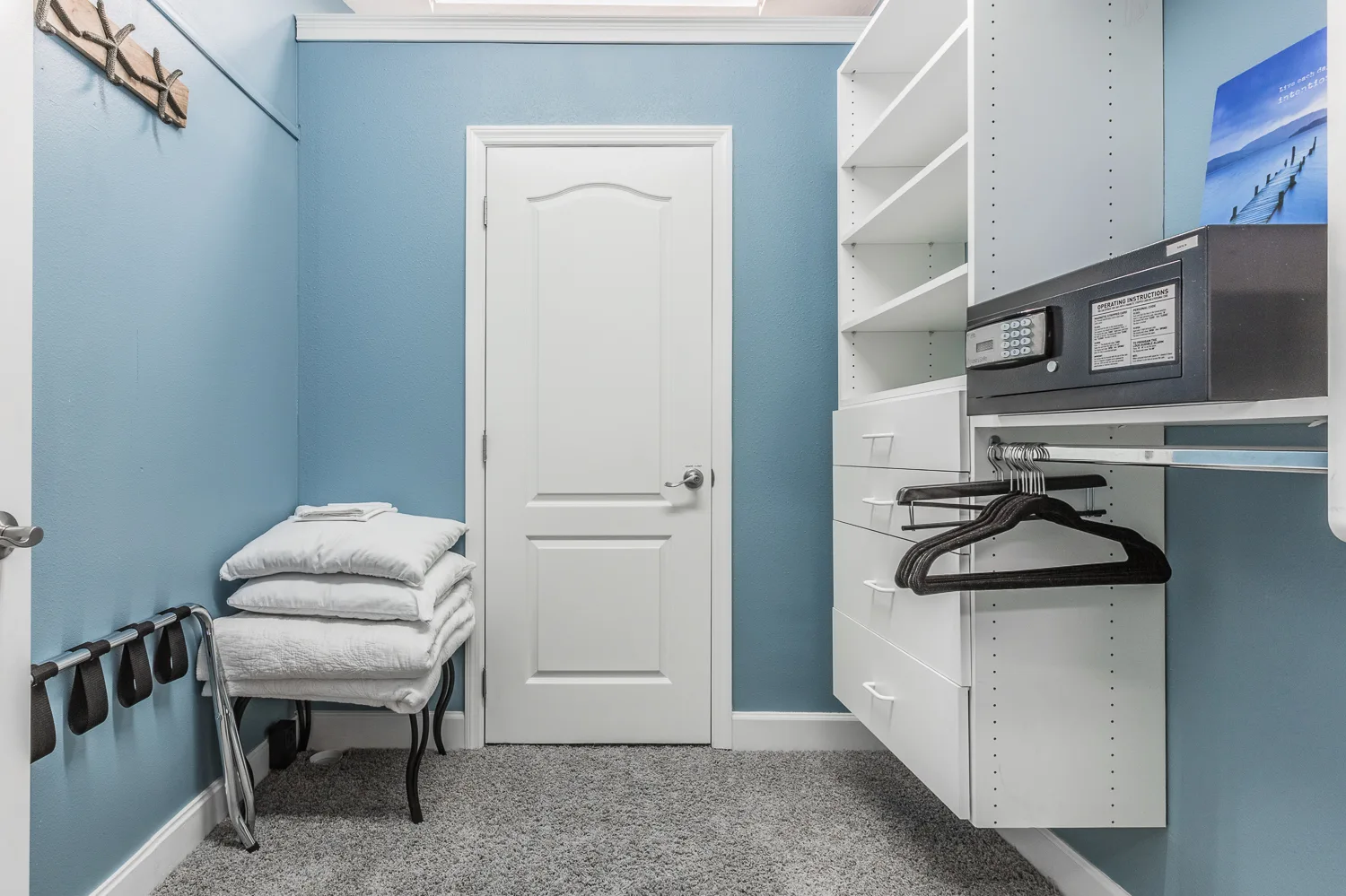 Walk-in closet in blue with safe, shelving and folded towels