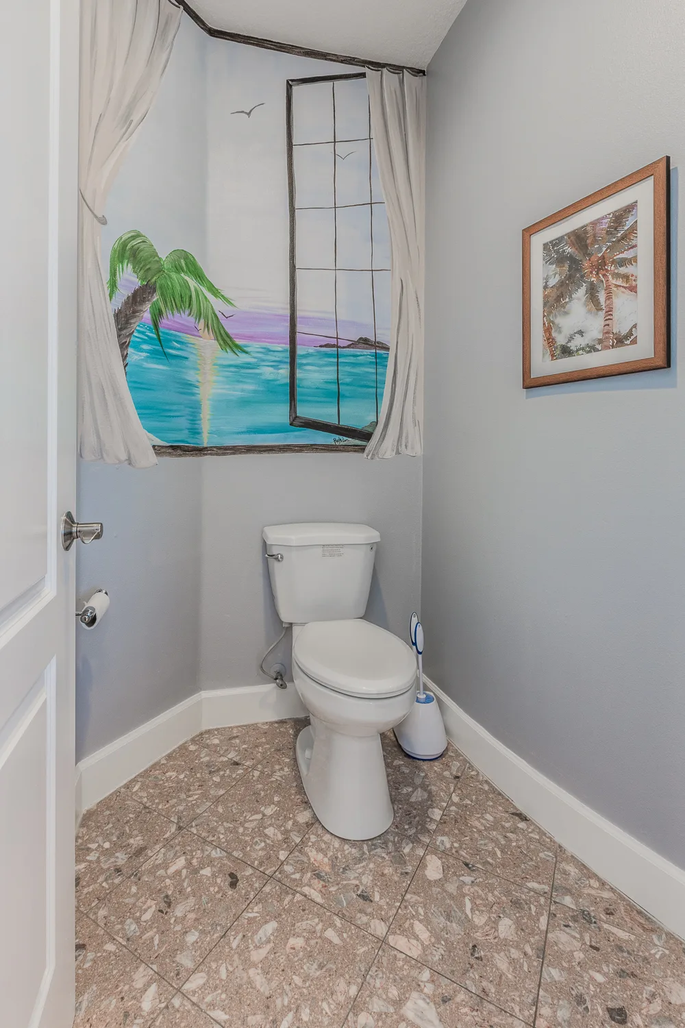 Powder room with hand-painted tropical beach mural above the toilet