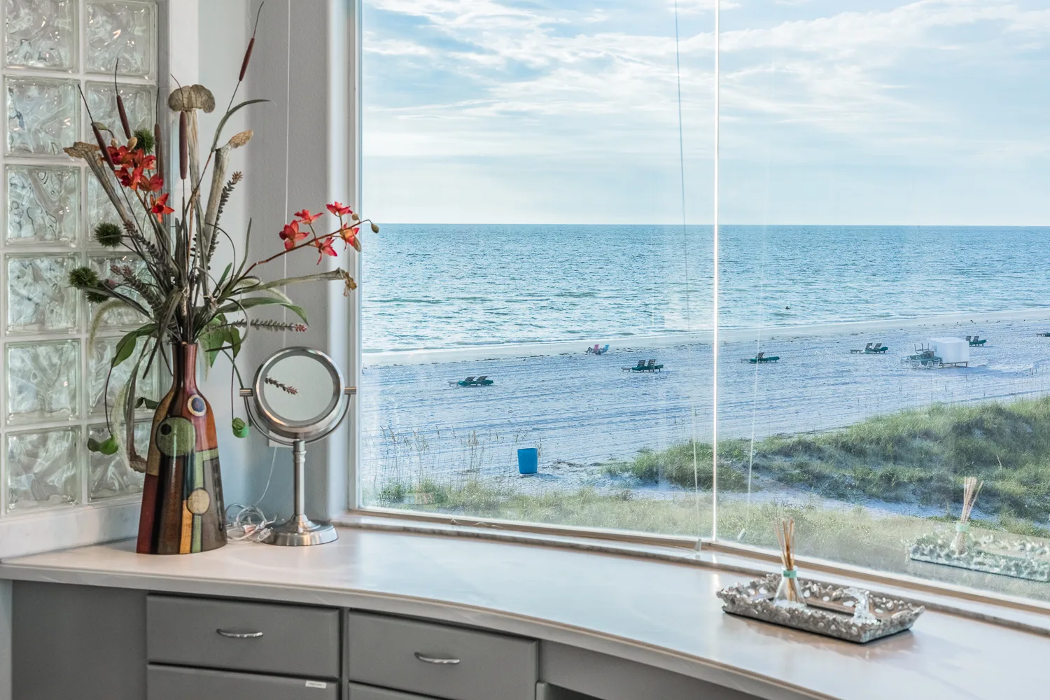 Vanity window overlooking the beach shoreline with lounge chairs below