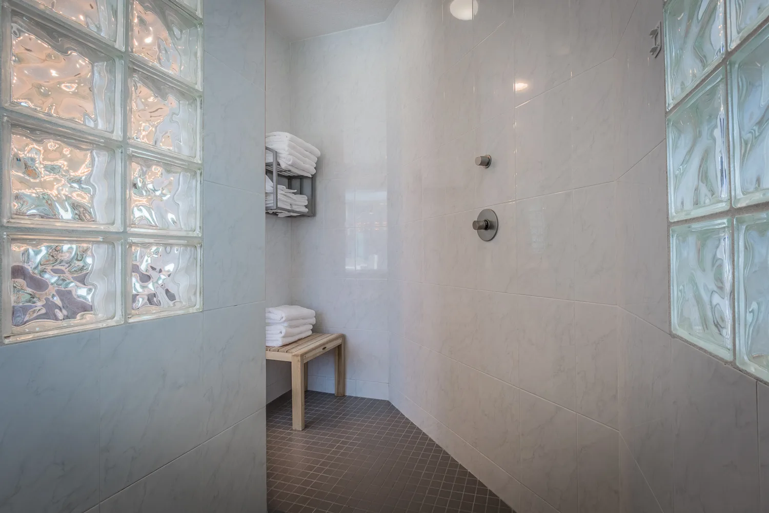Walk-in shower with glass block windows and towel bench