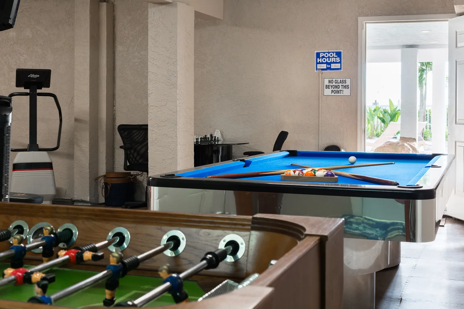 Game room with foosball and pool tables near the pool entrance