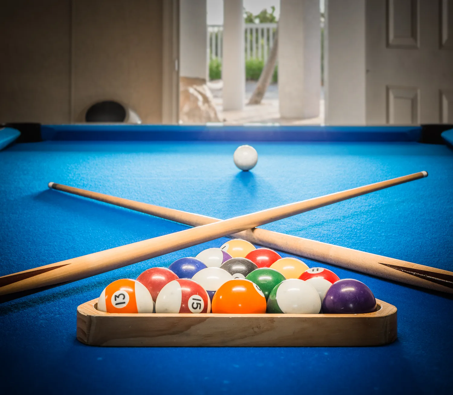 Racked billiard balls and crossed cues on a blue pool table