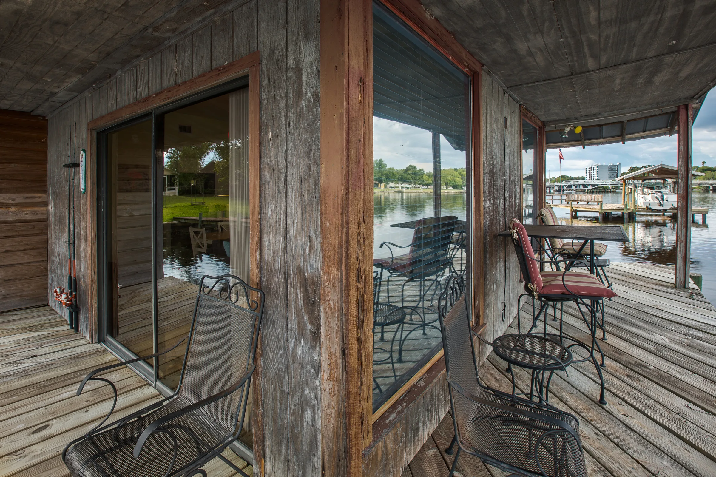 Weathered porch with iron bistro seating beside a lakefront dock