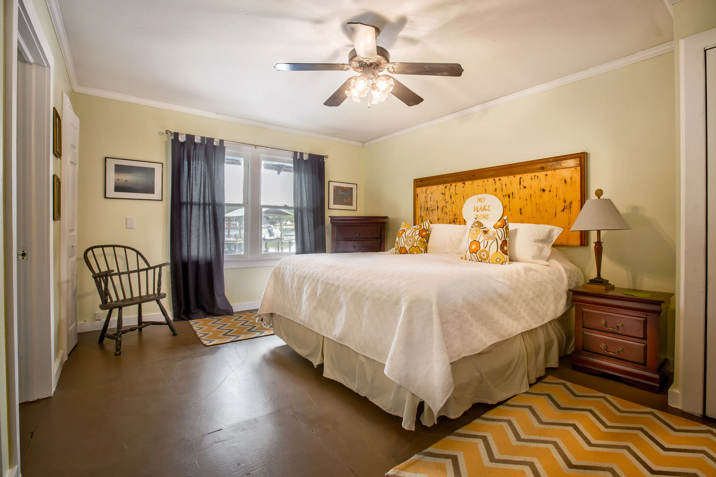 Yellow bedroom with rustic wood headboard, ceiling fan and chevron rug