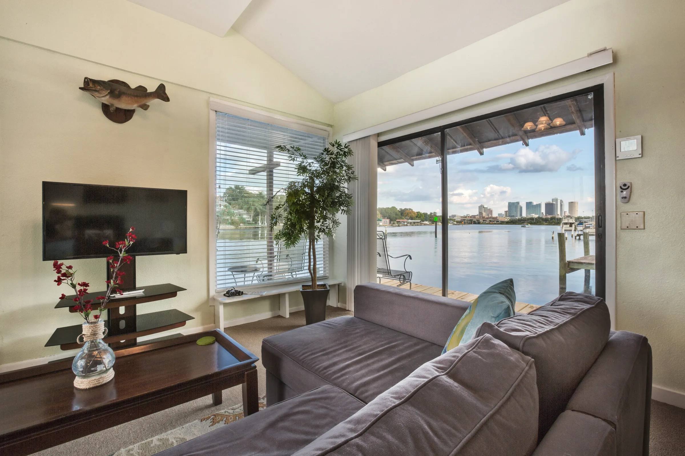 Living room with gray sectional facing wide bay and city skyline views