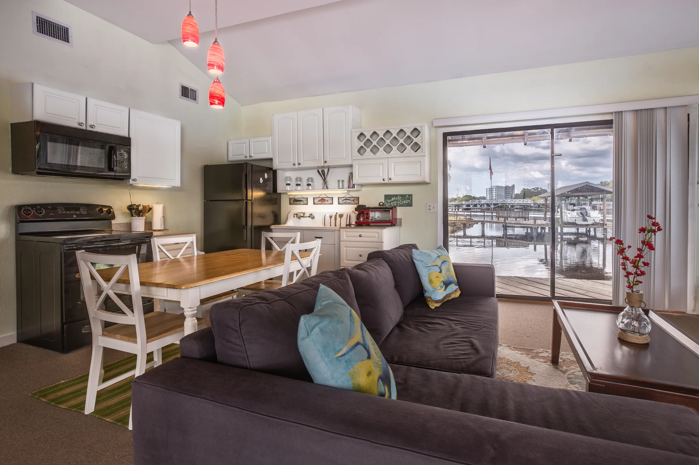 Open-plan cottage living space with kitchen, dining table and marina view