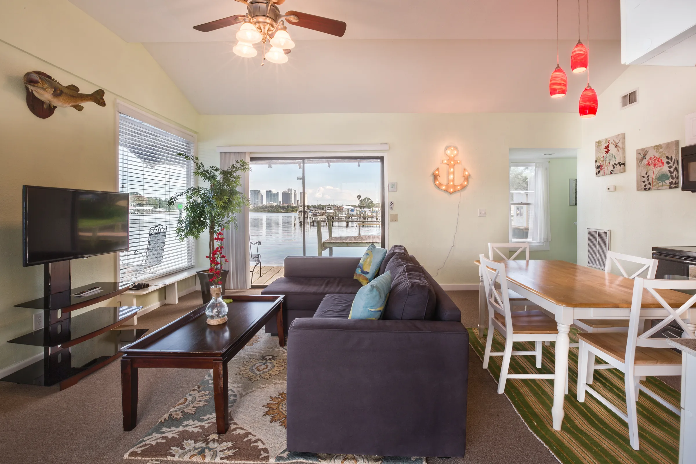 Coastal living room with sectional, dining nook and glass doors to water