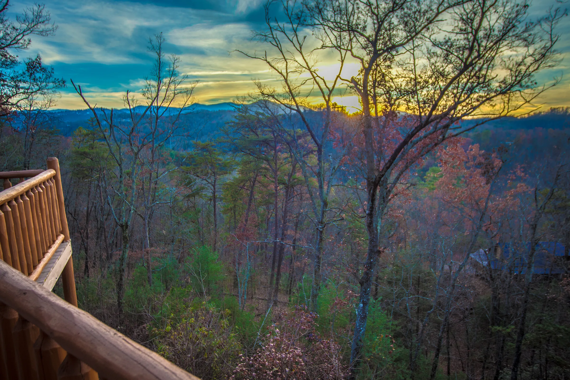 Sunset over forested mountain ridges viewed from a log deck