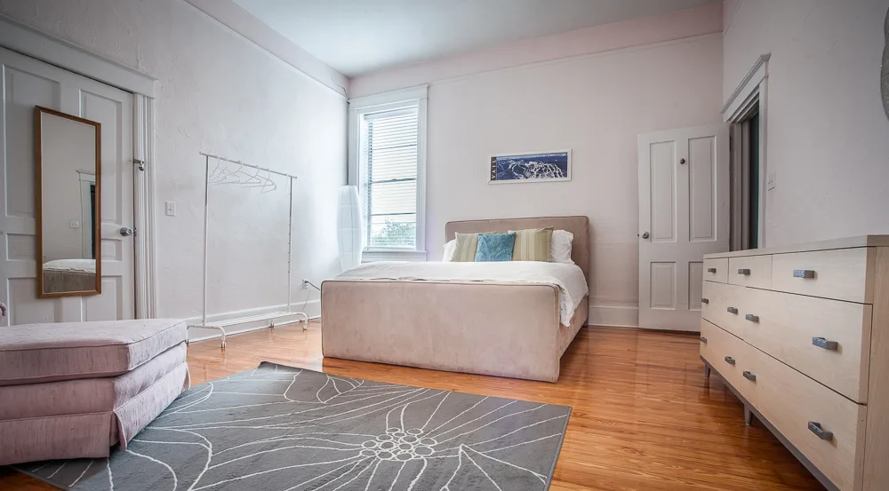 Airy neutral bedroom with upholstered bed, long dresser and chaise