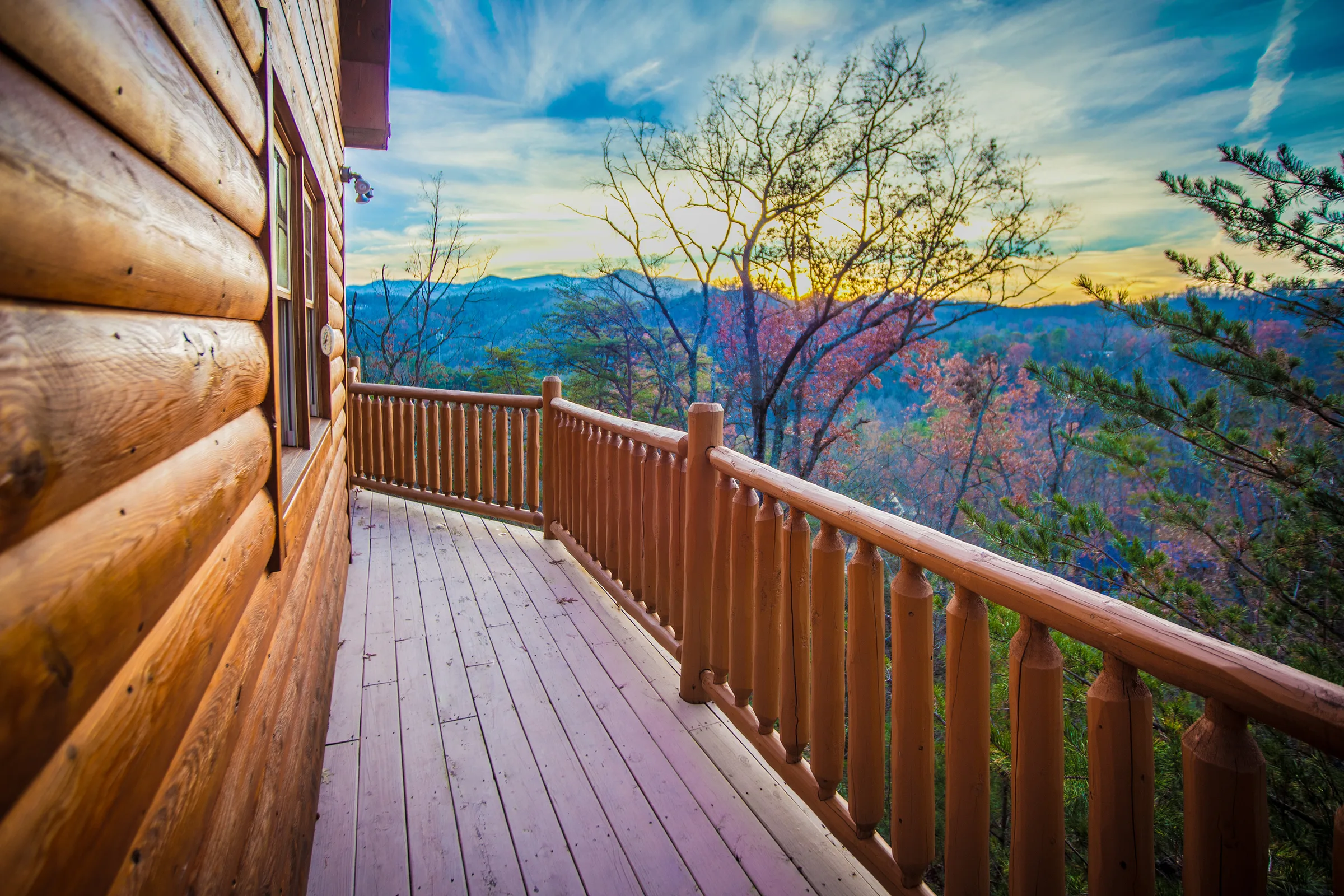 Log cabin deck with timber railing overlooking autumn mountain ridges