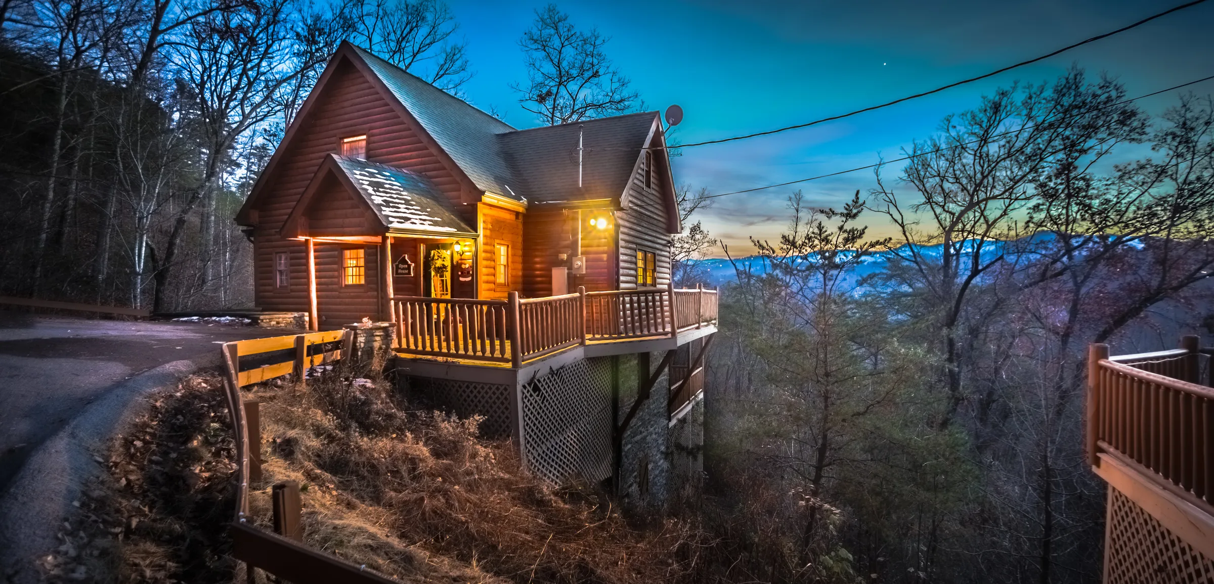 Log cabin glowing at twilight on a wooded mountainside