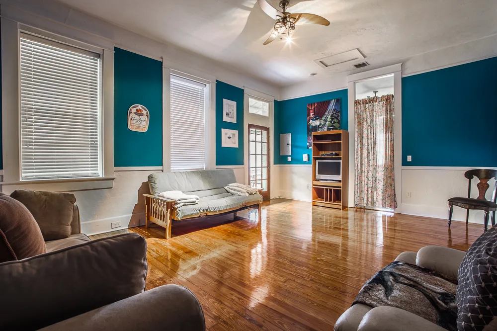 Teal living room with futon sofa, ceiling fan and polished wood floors