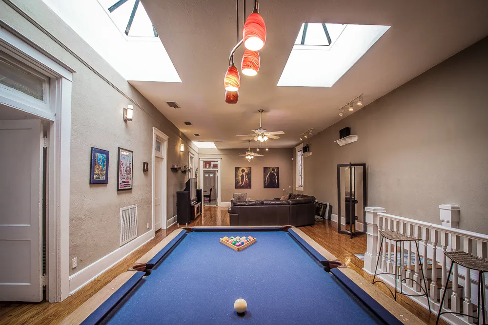 Game room with blue-felt pool table beneath twin skylights