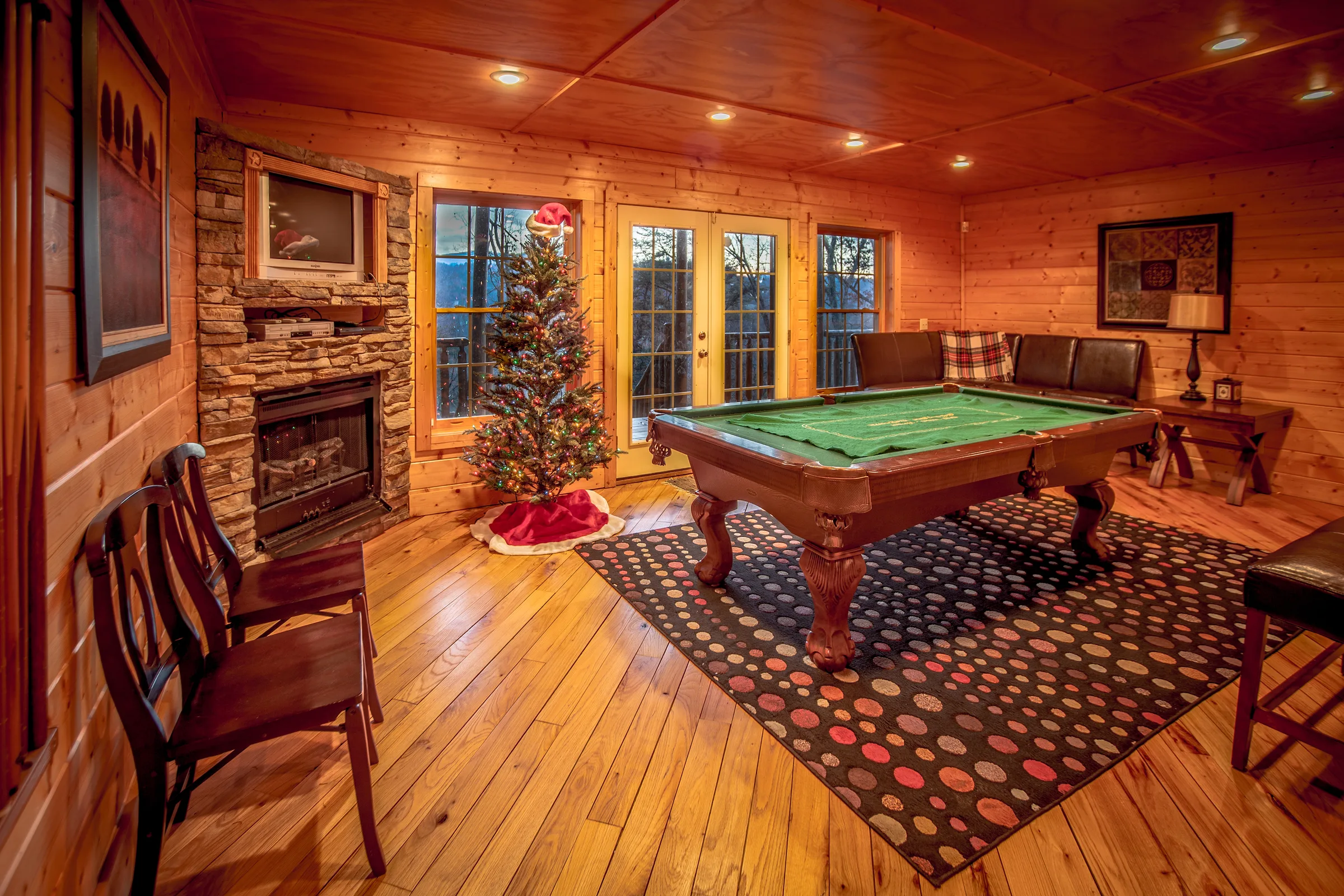 Cabin game room with pool table, stone fireplace and Christmas tree