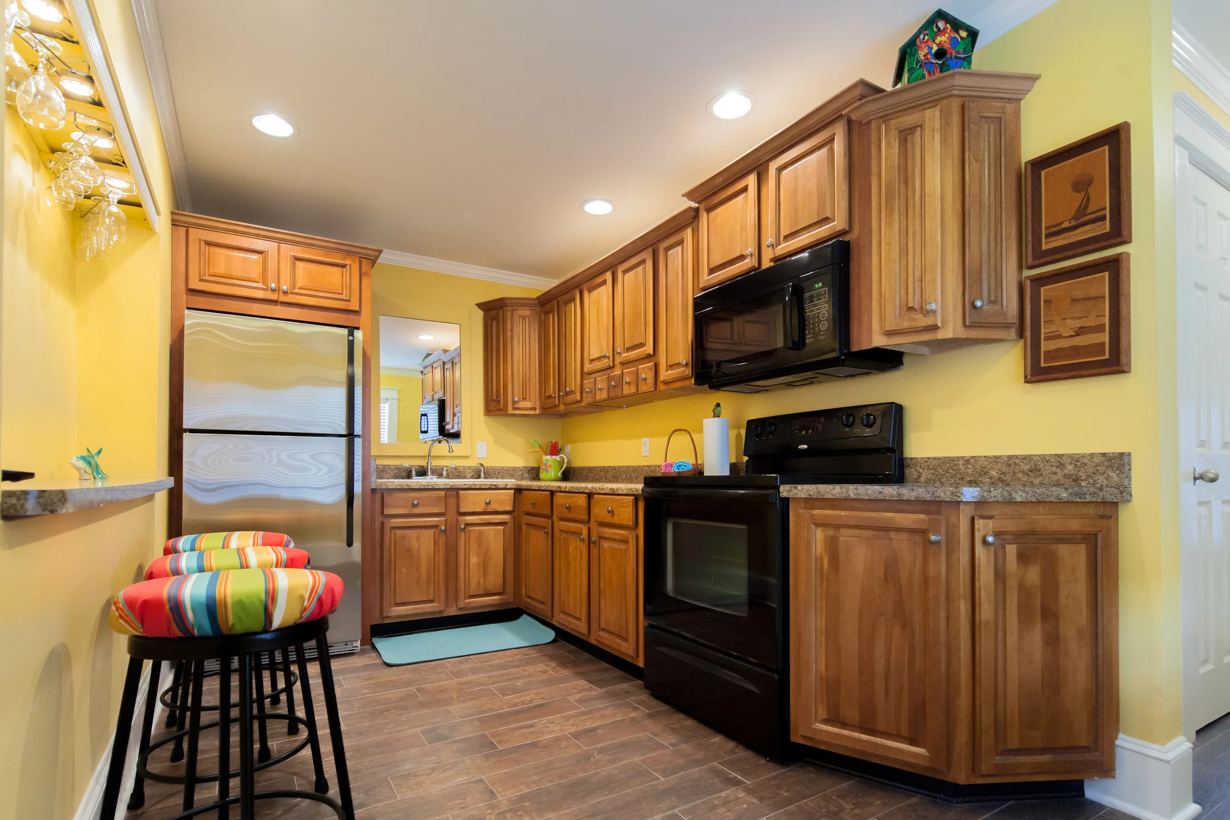 Yellow kitchen with oak cabinets, granite counters and striped barstools