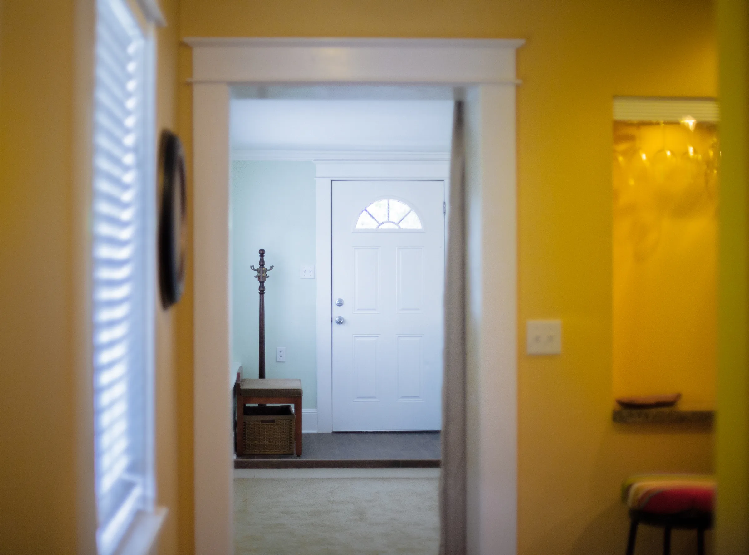 View through a doorway to a bright entry with white front door