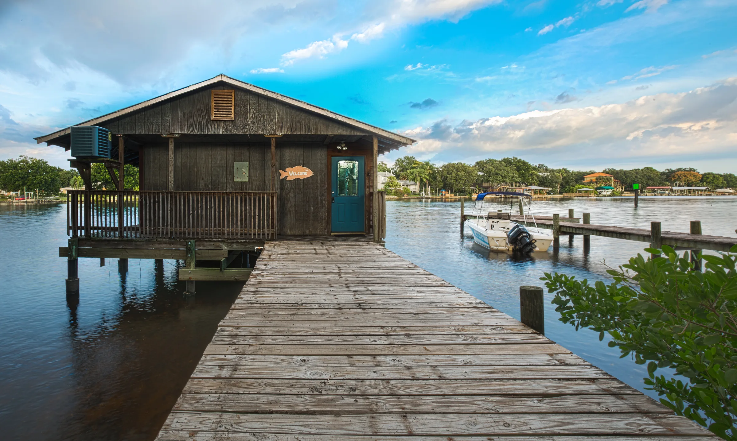Rustic stilt boathouse and long wooden dock on calm water