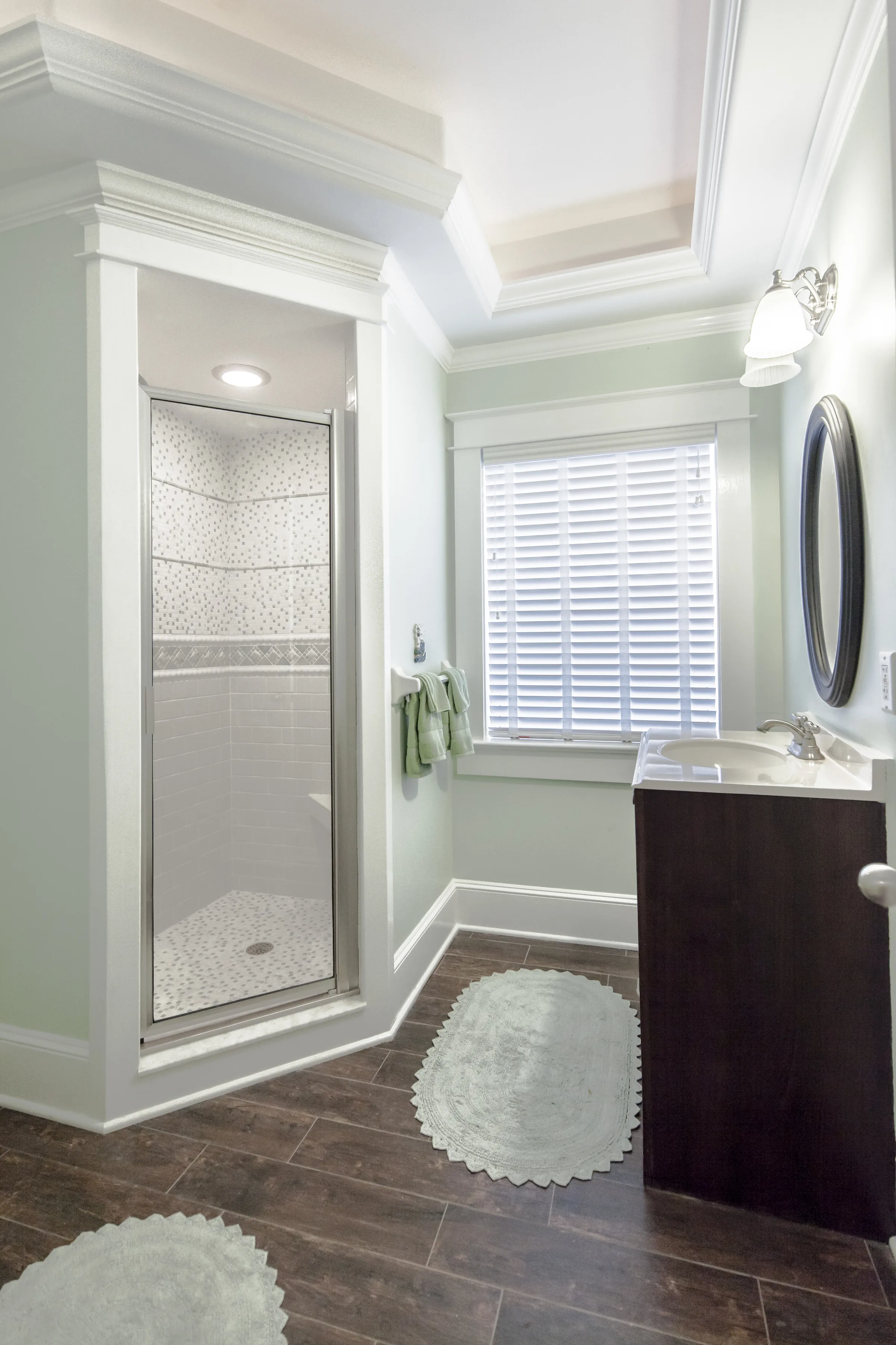 Pale green bathroom with walk-in shower, tray ceiling and dark vanity