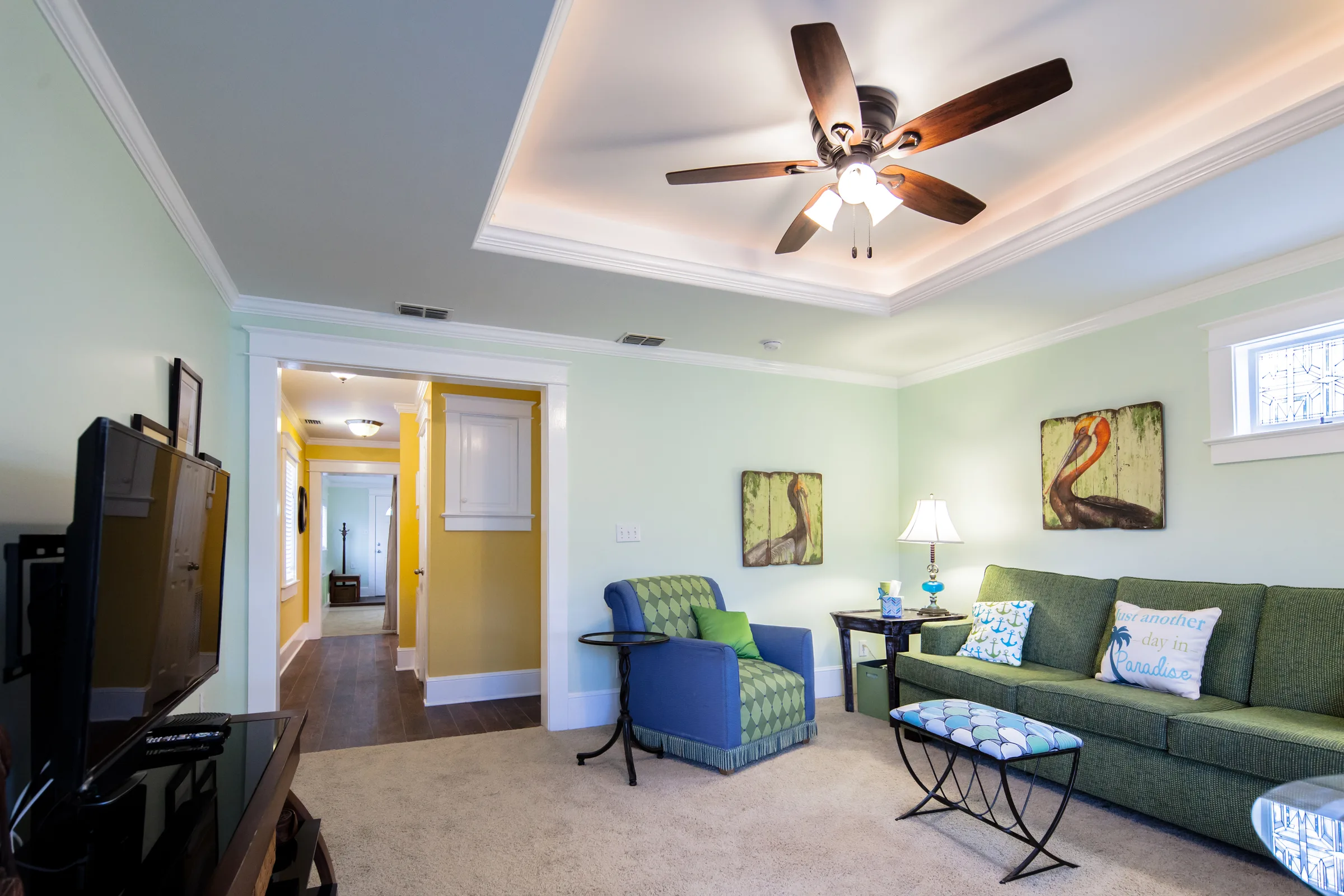 Living room with lighted tray ceiling, green sofa and pelican artwork