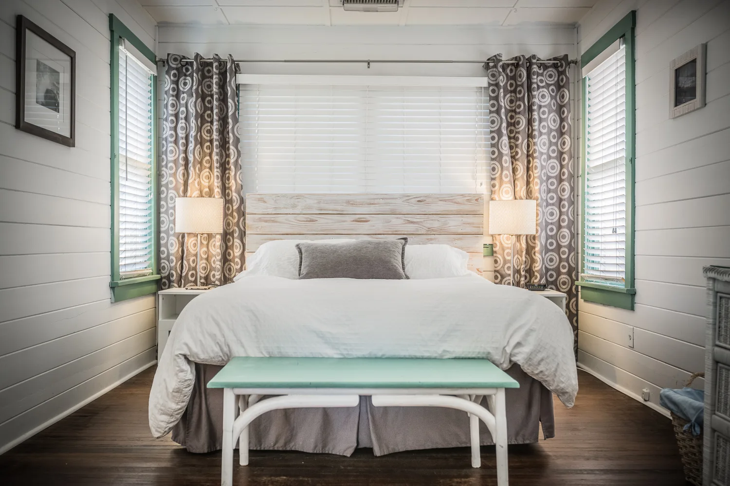 Bright bedroom with shiplap walls, king bed, and green-trimmed windows