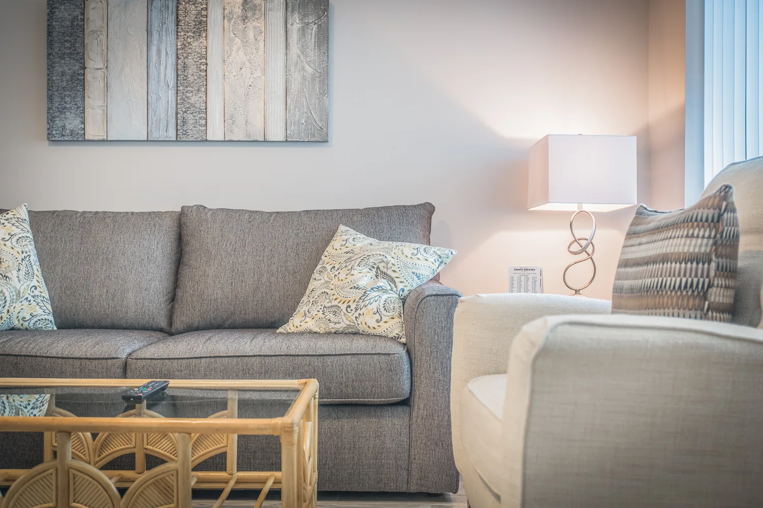 Neutral living area with gray sofa, paisley pillows, and rattan coffee table