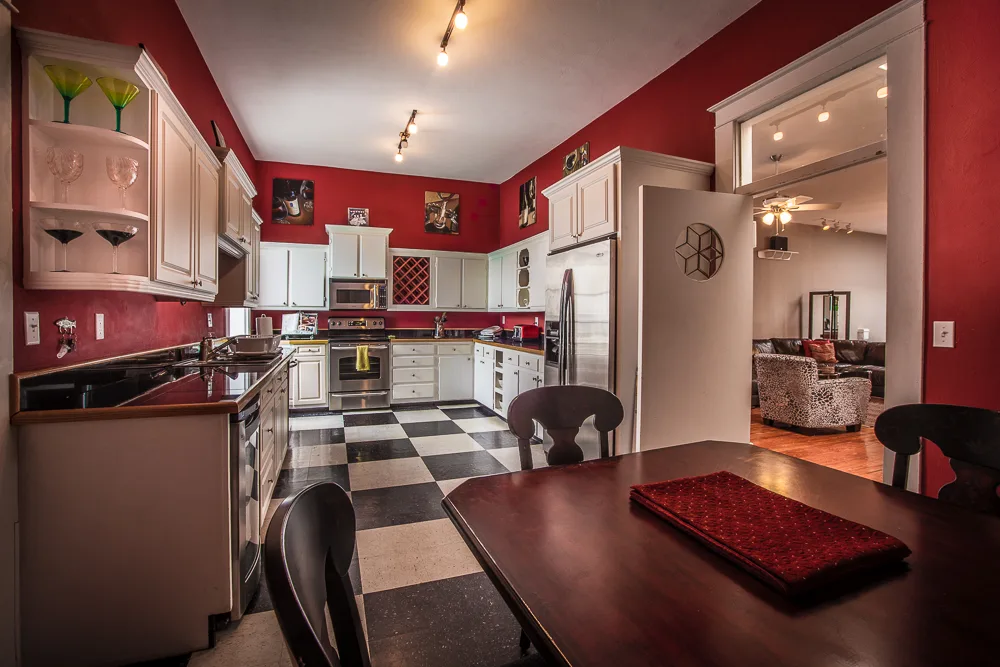 Red kitchen with checkerboard floor, stainless fridge and adjoining dining table
