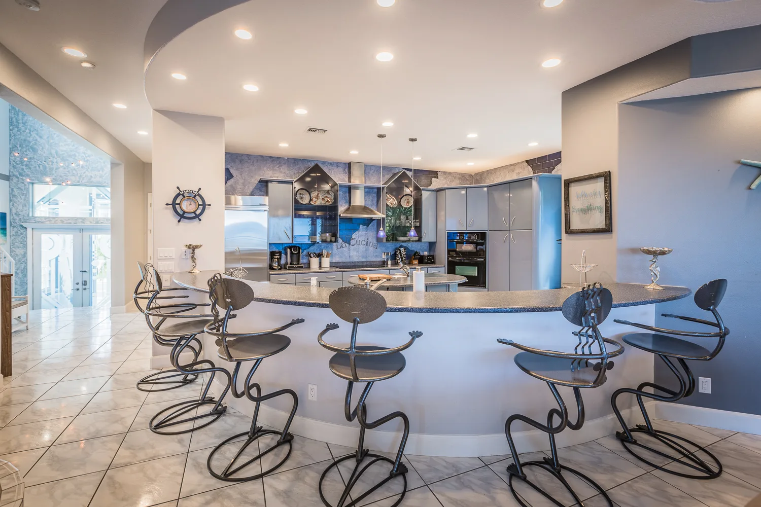 Curved kitchen bar with sculptural metal stools and nautical decor